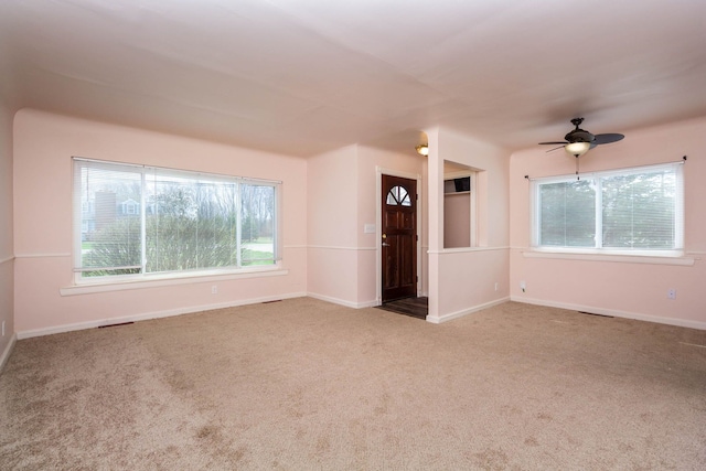 unfurnished living room with ceiling fan, baseboards, and carpet