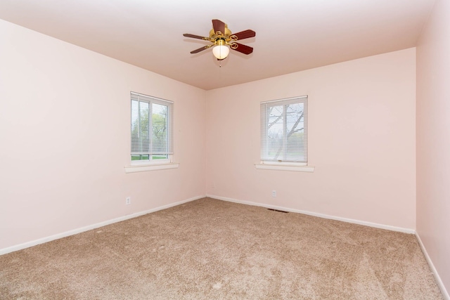 carpeted empty room with baseboards, ceiling fan, and visible vents
