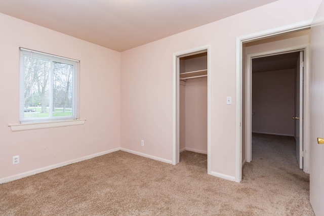 unfurnished bedroom with baseboards, light carpet, and a closet
