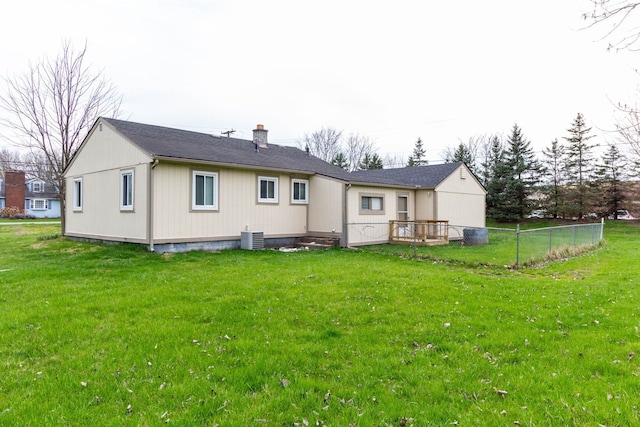rear view of property featuring fence, a yard, and a chimney