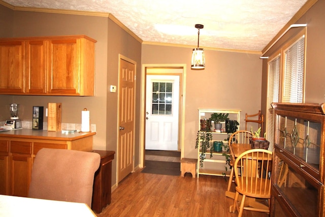interior space with wood finished floors, brown cabinets, ornamental molding, and hanging light fixtures