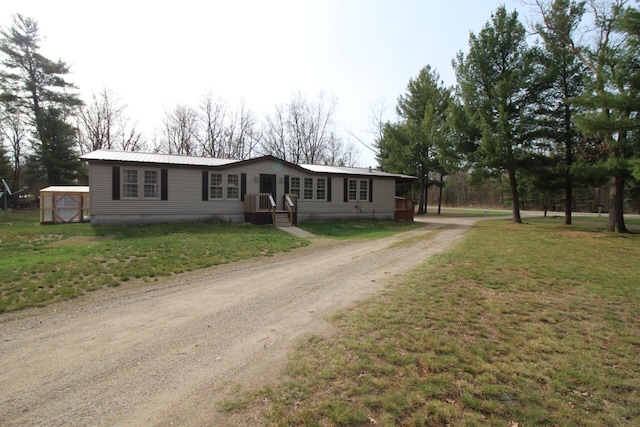 manufactured / mobile home featuring a front lawn, driveway, and metal roof