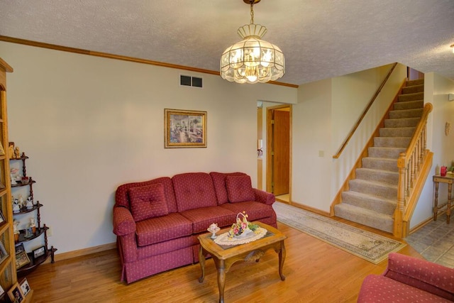 1414 Plains Rd, Leslie, MI 49251 - living room with a textured ceiling, stairway, baseboards, wood finished floors, and a notable chandelier