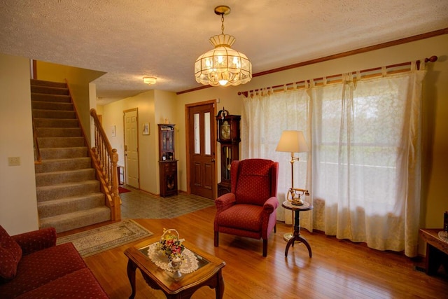 1414 Plains Rd, Leslie, MI 49251 - living room featuring a textured ceiling, wood finished floors, a chandelier, and stairs