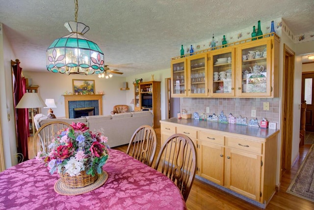 1414 Plains Rd, Leslie, MI 49251 - dining space with wood finished floors, a ceiling fan, a textured ceiling, and a fireplace