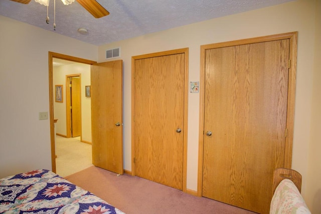 1414 Plains Rd, Leslie, MI 49251 - bedroom with carpet flooring, two closets, a ceiling fan, visible vents, and a textured ceiling