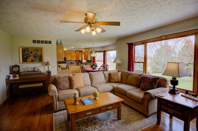 1414 Plains Rd, Leslie, MI 49251 - living room with dark wood-style floors, visible vents, a ceiling fan, and a textured ceiling