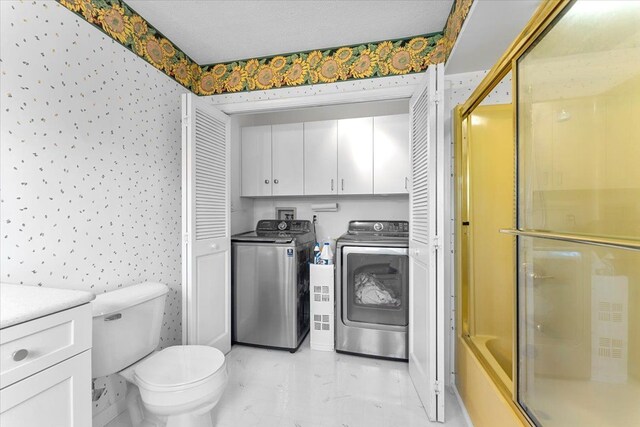 bathroom featuring washer and clothes dryer, a shower with shower door, toilet, and vanity