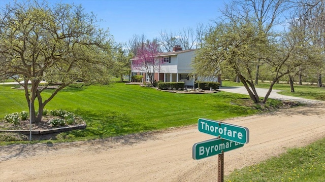 view of home's community featuring a yard and dirt driveway