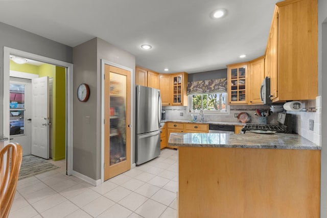 kitchen featuring decorative backsplash, glass insert cabinets, appliances with stainless steel finishes, stone counters, and a peninsula