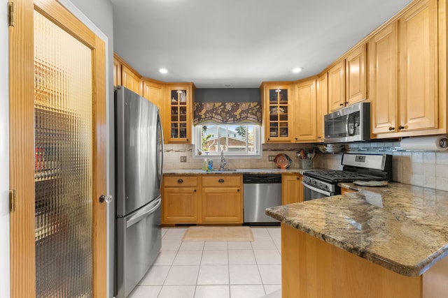kitchen featuring tasteful backsplash, stainless steel appliances, light tile patterned floors, and a sink