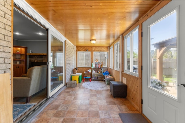 sunroom with stone finish flooring, wooden walls, and wooden ceiling