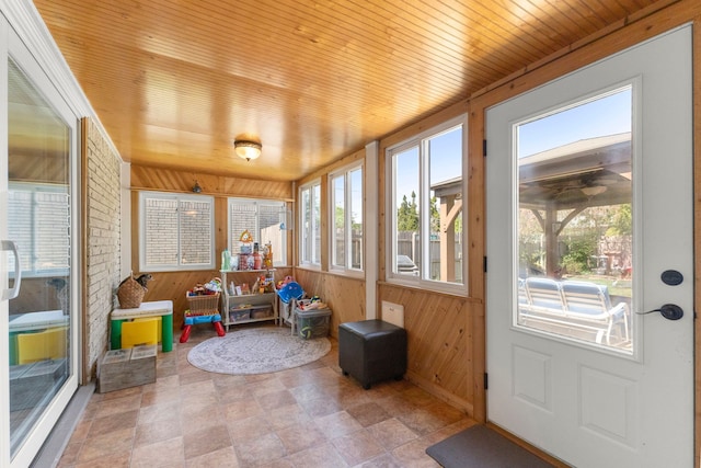 sunroom / solarium with stone finish flooring, wooden walls, and wood ceiling