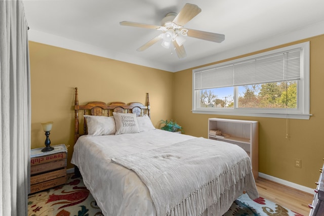 bedroom featuring baseboards, a ceiling fan, and light wood-style flooring