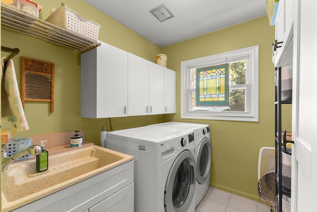 washroom featuring independent washer and dryer, cabinet space, a sink, baseboards, and light tile patterned flooring
