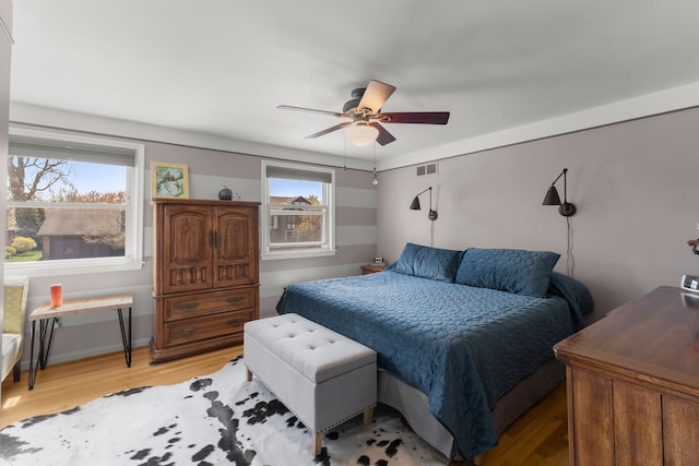 bedroom with light wood finished floors, visible vents, and ceiling fan