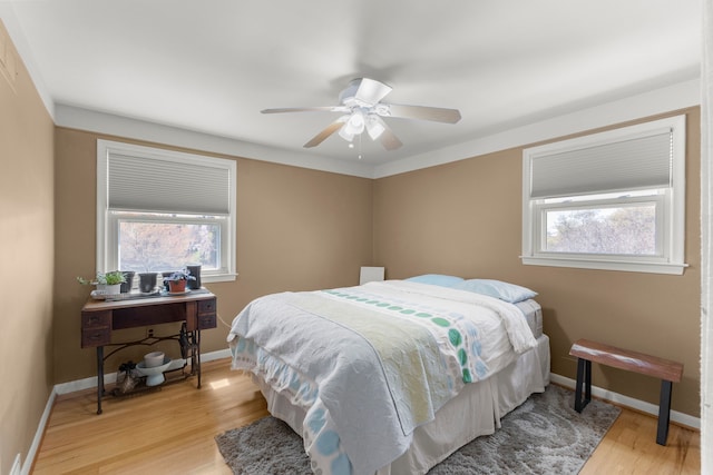 bedroom featuring baseboards, multiple windows, and light wood finished floors