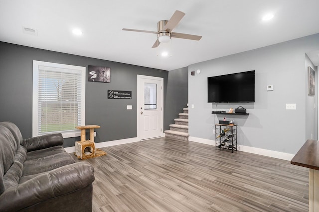 living room with baseboards, visible vents, wood finished floors, and ceiling fan
