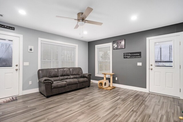 living room with light wood finished floors, a ceiling fan, recessed lighting, and baseboards