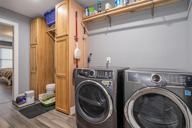 laundry area featuring baseboards, wood finished floors, cabinet space, and washing machine and dryer