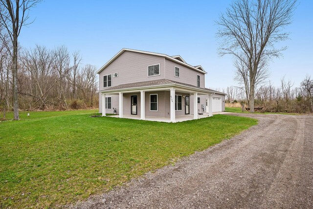 view of side of home featuring covered porch, dirt driveway, a yard, and an attached garage