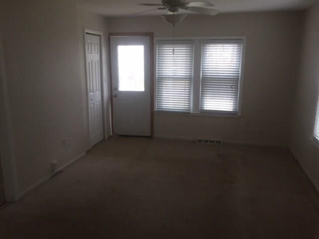 spare room featuring ceiling fan, light colored carpet, and baseboards