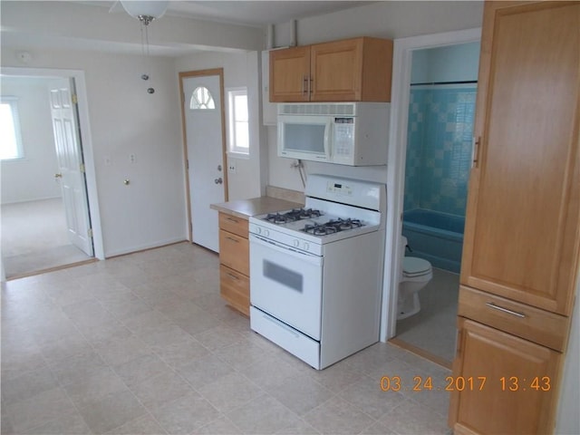 kitchen with white appliances, plenty of natural light, light countertops, and baseboards