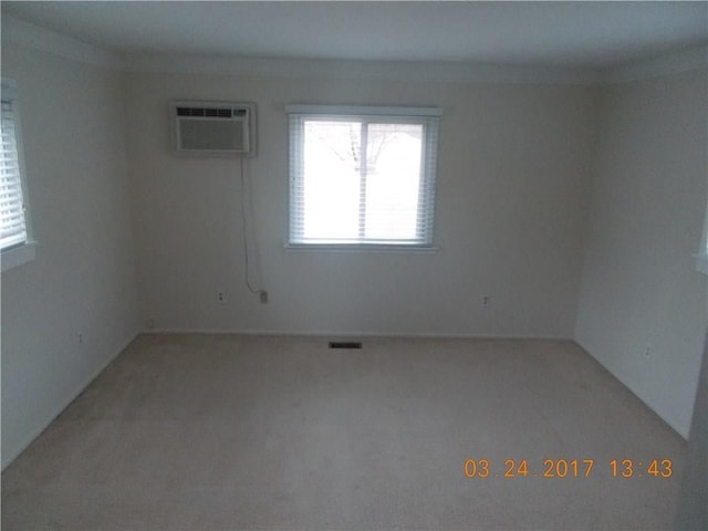 empty room featuring a wall unit AC and light carpet