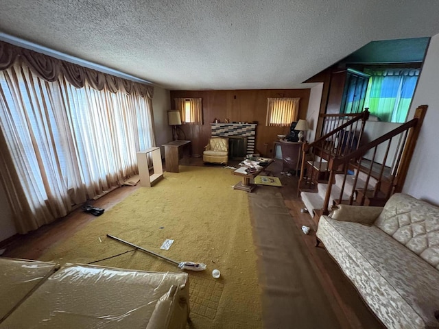 living room featuring a textured ceiling, a stone fireplace, and carpet