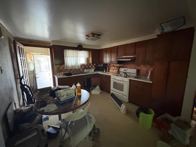 kitchen featuring white gas range, a sink, under cabinet range hood, and tasteful backsplash