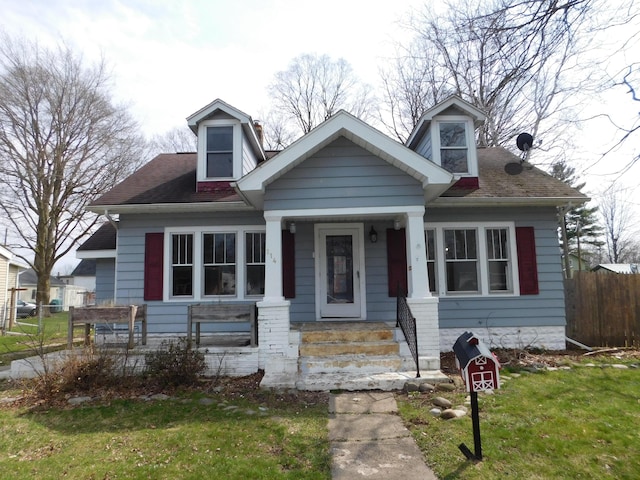 view of front of home with a shingled roof, fence, and a front lawn