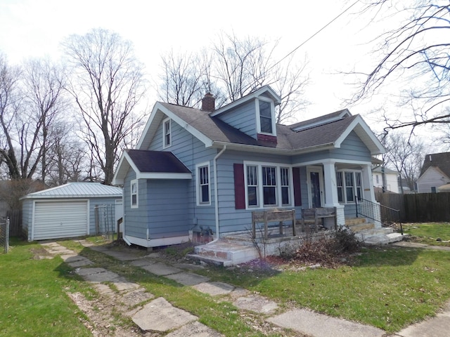 view of front of home with a chimney, a detached garage, a shingled roof, an outbuilding, and covered porch