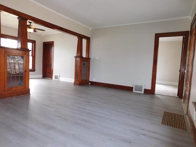 unfurnished living room with wood finished floors, visible vents, ceiling fan, and ornamental molding