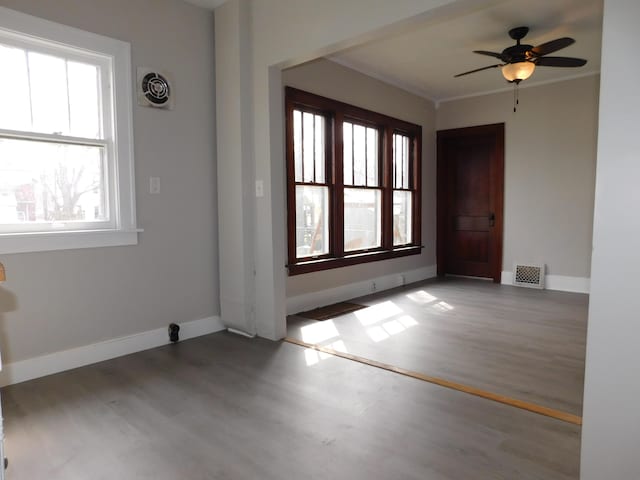 interior space featuring wood finished floors, visible vents, ceiling fan, and baseboards