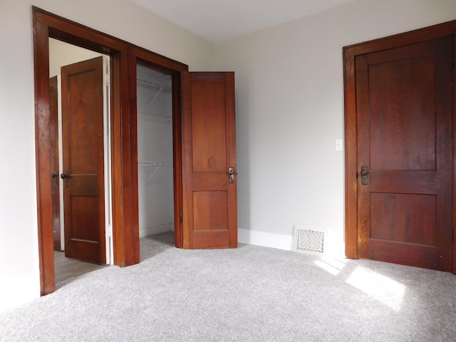 unfurnished bedroom featuring visible vents, a spacious closet, a closet, and carpet