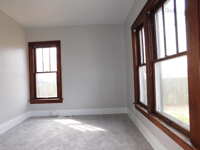 carpeted spare room with visible vents and baseboards