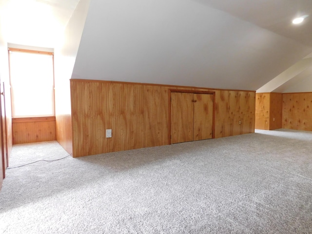 additional living space featuring wooden walls, carpet flooring, and lofted ceiling