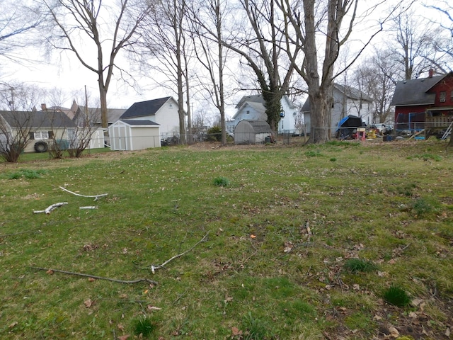 view of yard with an outbuilding, a shed, a residential view, and fence