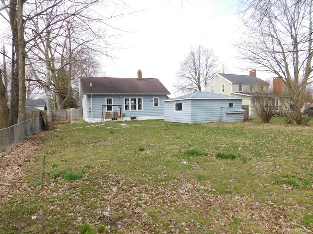 back of house with a chimney, fence, and a yard