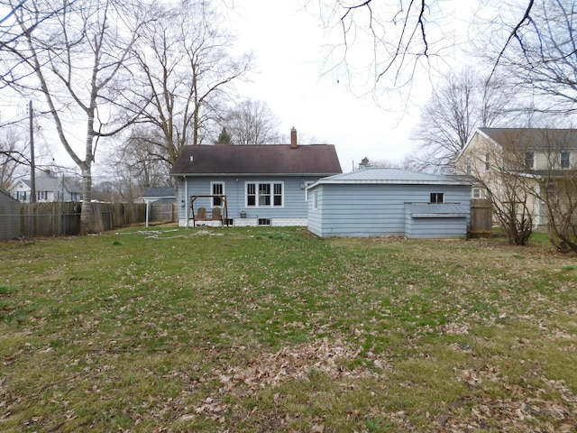 rear view of property with a chimney, fence, and a lawn