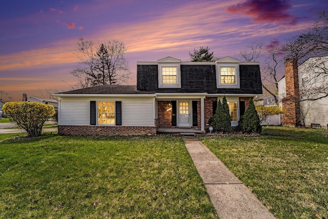 view of front of home featuring brick siding, a shingled roof, and a front lawn