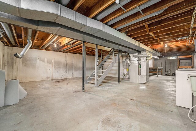 unfinished basement with heating unit, water heater, stairway, and washer / clothes dryer