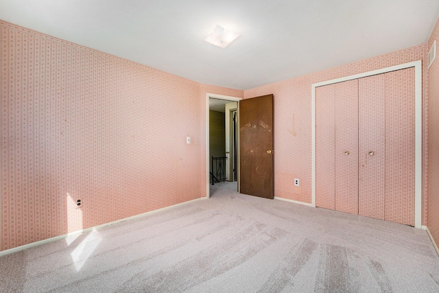 unfurnished bedroom featuring wallpapered walls, carpet floors, and a closet