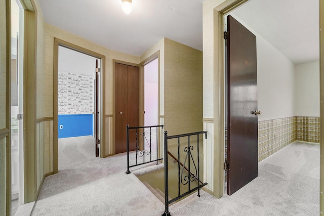 hall with an upstairs landing and carpet floors