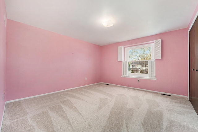 spare room featuring visible vents, light carpet, and baseboards