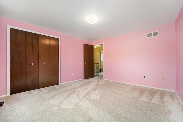 unfurnished bedroom featuring visible vents, a closet, baseboards, and light carpet