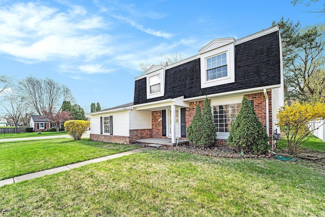 colonial inspired home featuring a front lawn, a shingled roof, and brick siding