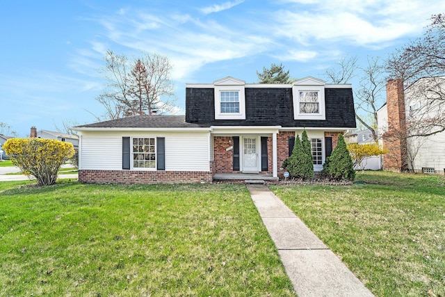 view of front of home with roof with shingles, a front yard, and brick siding