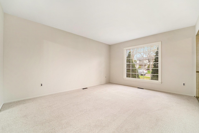 carpeted spare room with visible vents and baseboards