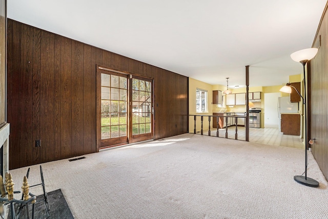 living room featuring wood walls, visible vents, and light carpet